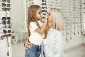 A woman and her daughter trying on eyeglasses in a stylish optical store.